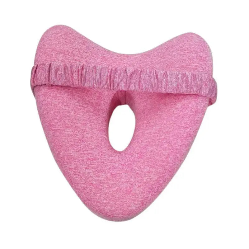 Pink orthopedic knee pillow with center cutout and adjustable strap for pregnancy and leg alignment support.